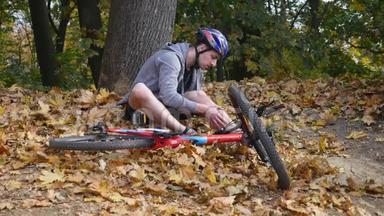 一个年轻人从一辆自行车上摔下来后坐在公园里，缓解膝盖的疼痛，在公园里骑一辆危险的自行车